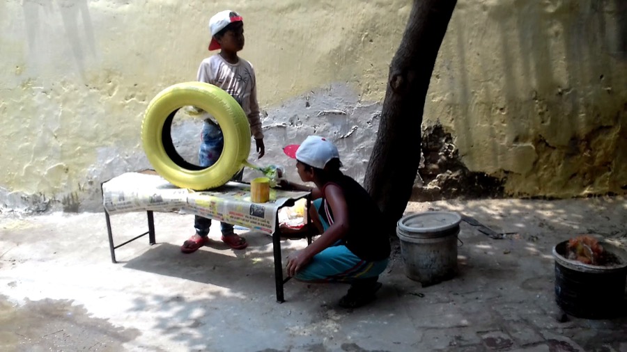 Children painting a tyre installation in the schoolyard